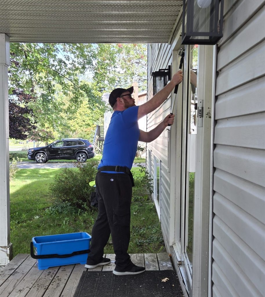 Fundy Blue window cleaner in a blue shirt cleaning the glass door of a building entrance